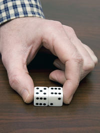 Cropped hand holding dice over table
