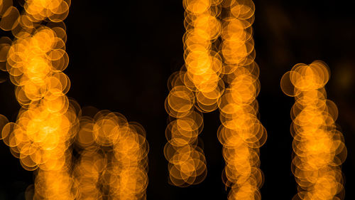 Low angle view of illuminated lanterns hanging against black background