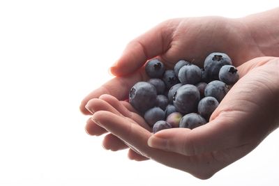 Close-up of hand holding berries over white background