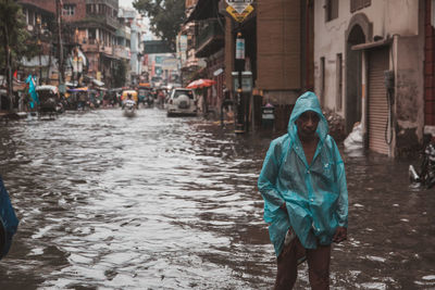Portrait of man standing on wet street in rain