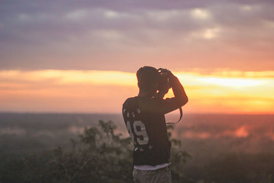 Full length of woman standing on field against sky during sunset