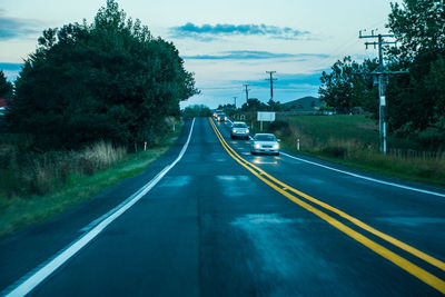 Road passing through city against sky