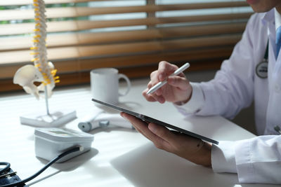 Midsection of doctor working on table