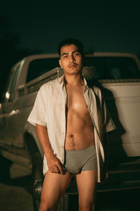 Portrait of young woman standing against car