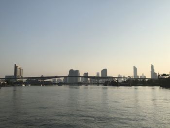 Sea by buildings against clear sky