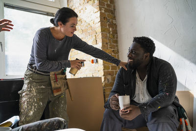 Multiracial male and female carpenters talking during coffee break in apartment