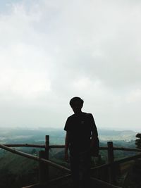 Rear view of man looking at sea against sky