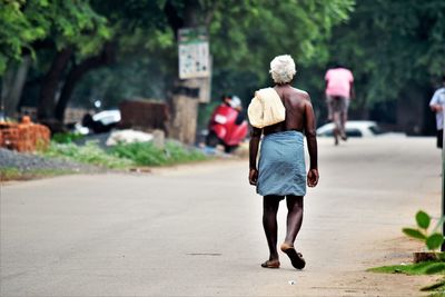 Rear view of woman walking on road