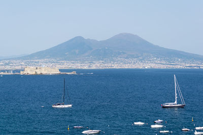 Sailboats sailing on sea against clear sky