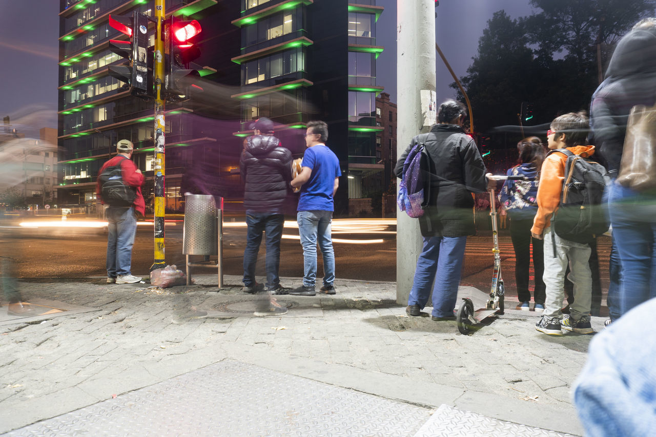 PEOPLE WALKING ON STREET IN CITY AT NIGHT