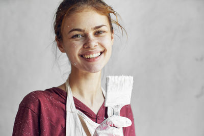 Portrait of smiling young woman holding paintbrush