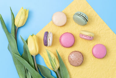 Five macaroons on yellow paper on a blue background.