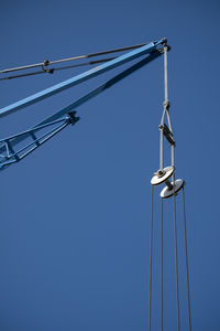 Low angle view of crane against clear blue sky