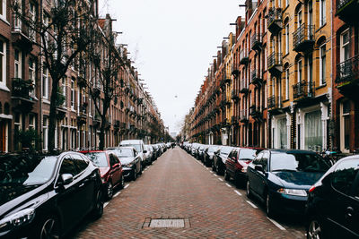 Road amidst cars parked in city