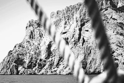 Scenic view of sea by mountain against sky