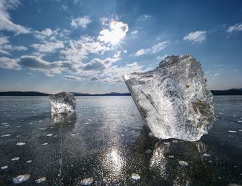 Transparent ice piece on lake. crystal clear piece of ice squeezed lake, sun rays create reflectio.