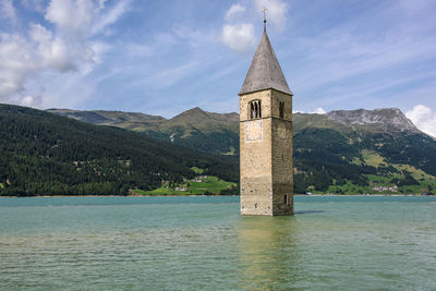 Cross on building by mountain against sky