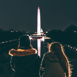 Rear view of female friends looking at illuminated washington monument at night