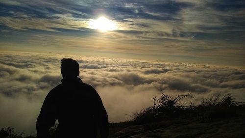 Rear view of silhouette man looking at sunset sky