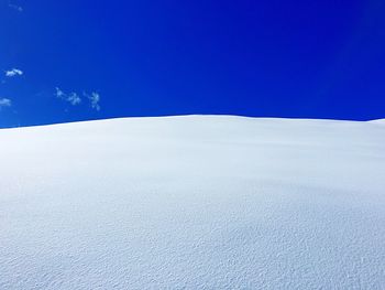 Snow covered landscape against blue sky