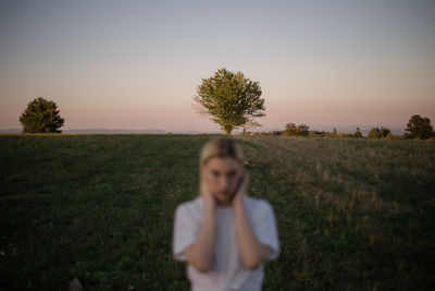 Woman standing on field against sky during sunset