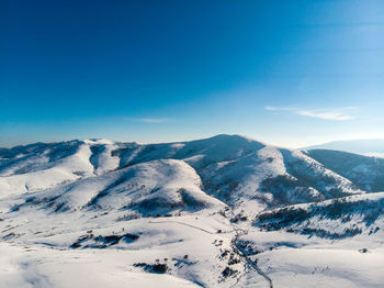 Scenic view of snowcapped mountains against blue sky