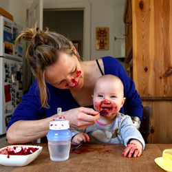 Woman feeding baby at kitchen table 