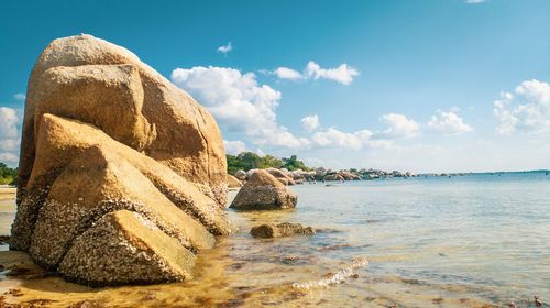 Scenic view of rocks on beach against sky