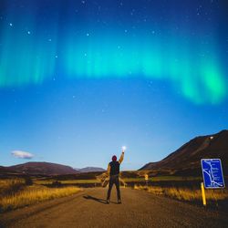 Full length of man with arms raised against sky at night