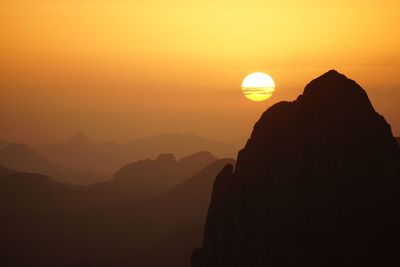 Scenic view of silhouette mountains against orange sky