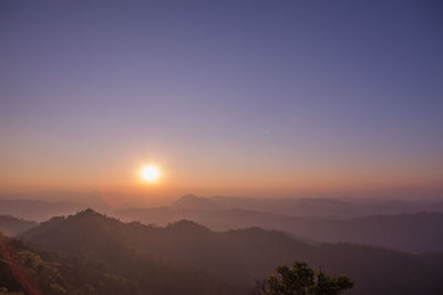 Scenic view of silhouette mountains against clear sky at sunset