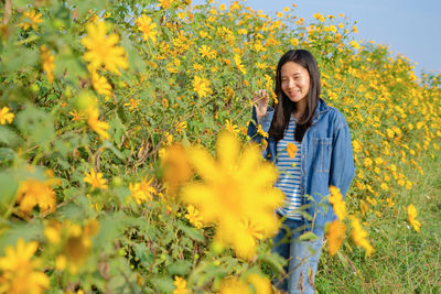Portrait of smiling woman standing by flowering plants