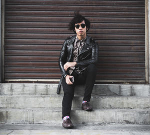 Portrait of young woman sitting against shutter