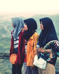 Rear view of women standing against the sky