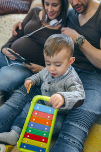 Parents with son using digital tablet while sitting in living room at home