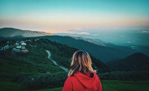 Rear view of woman looking at mountains against sky