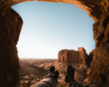 You couple has low angle view of rock formations through double arch in arches national park moab