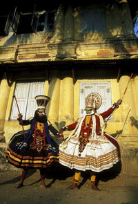 Kathakali dancers dancing against old house