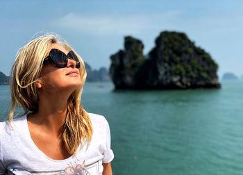 Portrait of young woman in sunglasses against sea