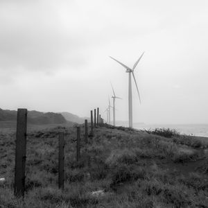 Wind turbines on field against sky