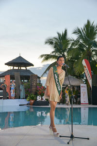 Woman standing by swimming pool against sky