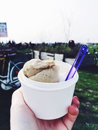 Cropped image of person holding ice cream against sky