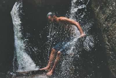 Young man standing at waterfall