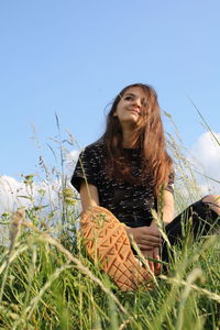 Beautiful young woman on field against clear sky