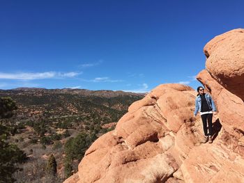 Rear view of man standing on cliff against sky