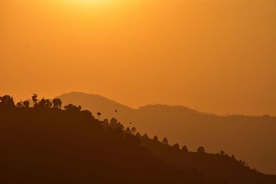 Scenic view of silhouette mountains against orange sky