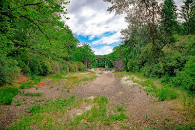 Footpath by arch bridge against sky