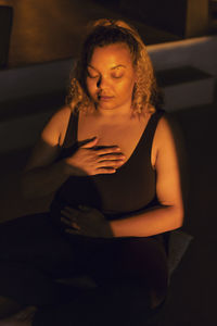 Woman with eyes closed meditating in retreat center at sunset