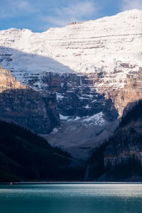 Scenic view of lake by snowcapped mountains against sky