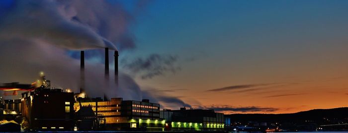 Smoke emitting from factory against sky during sunset